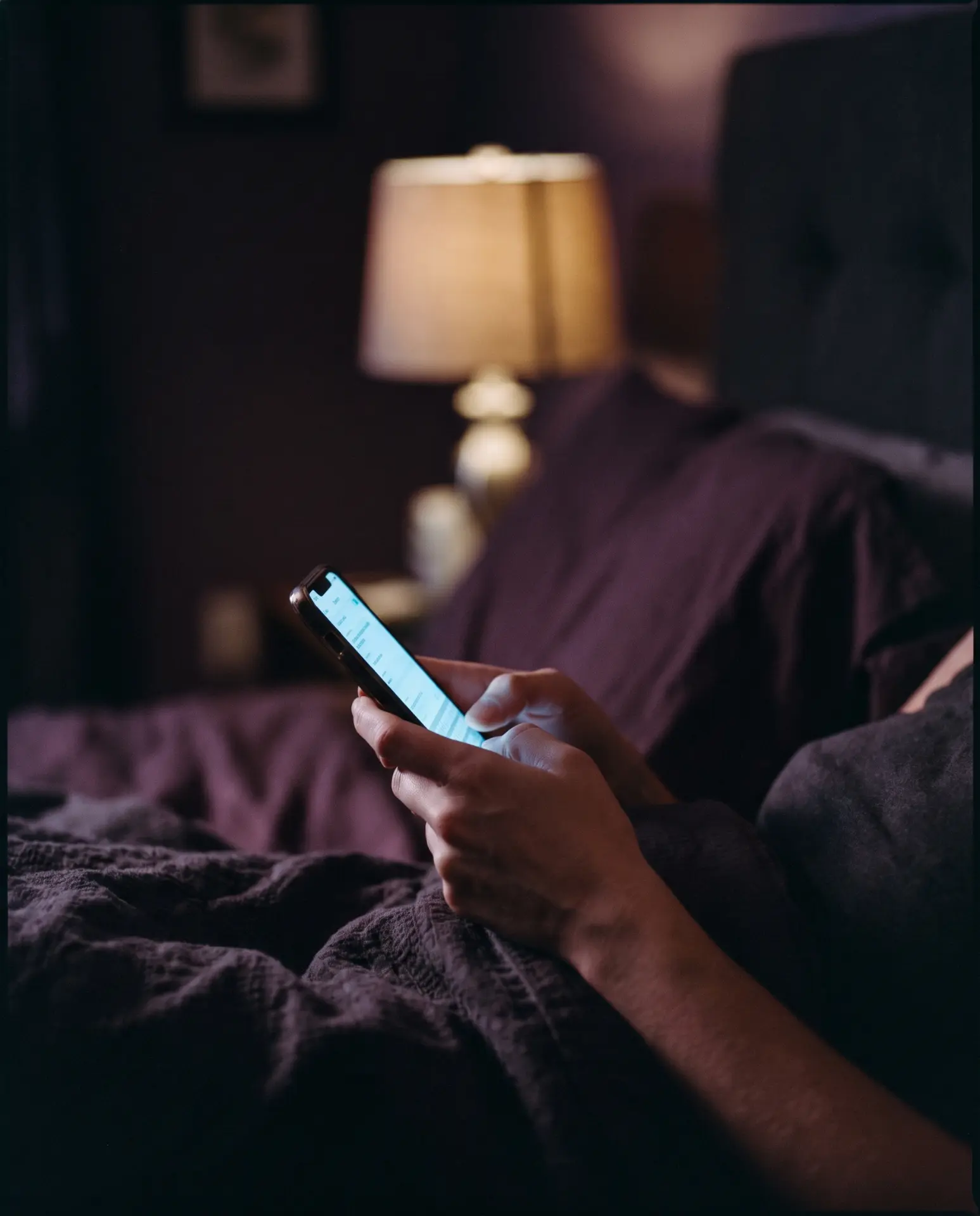 Hands holding a lit phone screen at night